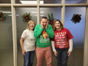 Jan Nelson, Kevin Wangen, and Shara Fischer in their festive Christmas Sweaters